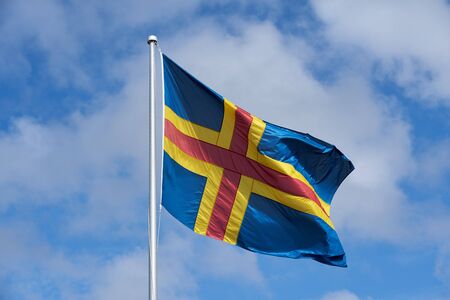The flag of Ãland against a blue sky.の写真素材