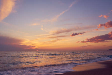 Sunset on the Mediterranean sea, waves roll on the sandy beach.の写真素材