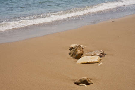 Stones on tropical sandy beach with blurred waves on the backgroundの写真素材