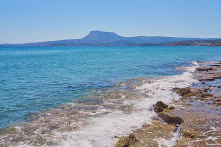 Waves with foam on Aegean sea coast in Crete Greece