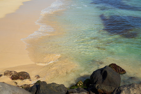Rocks and waves on a sandy tropical beach.の写真素材