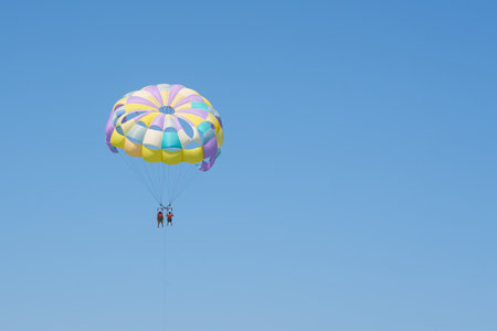 Colorful parasailing parachute against a clear blue sky.の写真素材