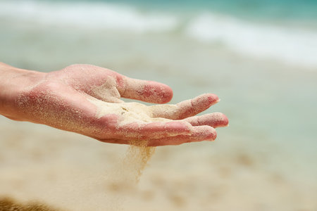 Beach sand falls from a hand of a womanの写真素材