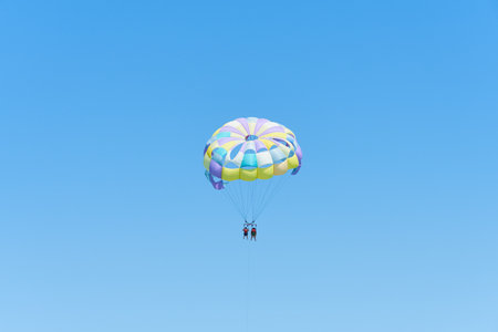 Colorful parasailing parachute against a clear blue skyの写真素材