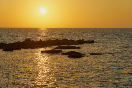 A colorful sunset on the rocky Mediterranean coast.の写真素材