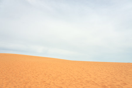 Sand dune in the desert with clouds in the backgroundの写真素材