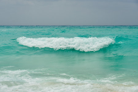 Waves and foam on a tropical sandy beachの写真素材