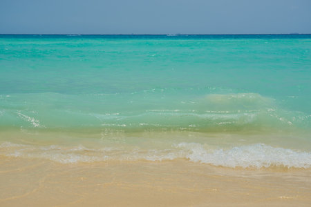 Waves and foam on a tropical sandy beach.の写真素材