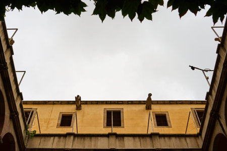 The courtyard has a yellow building with a cloudy sky in the background