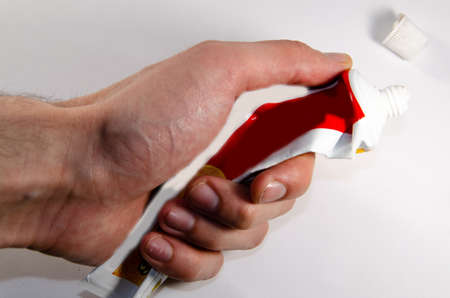 Tube of toothpaste compressed in handの写真素材