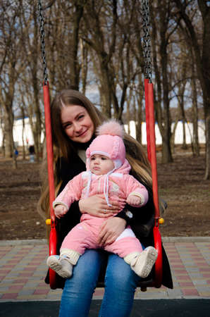 Mom plays on a bright playground with a small child in the street, nomads, a house during the dayの写真素材
