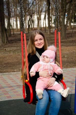 Mom plays on a bright playground with a small child in the street, nomads, a house during the dayの写真素材