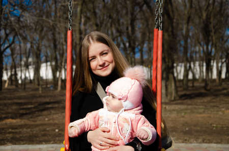 Mom plays on a bright playground with a small child in the street, nomads, a house during the dayの写真素材