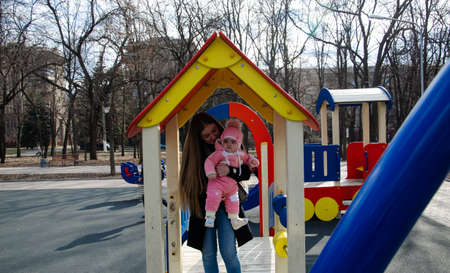 Mom plays on a bright playground with a small child in the street, nomads, a house during the dayの写真素材