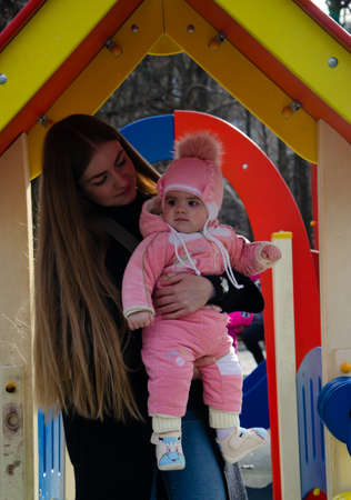 Mom plays on a bright playground with a small child in the street, nomads, a house during the dayの写真素材
