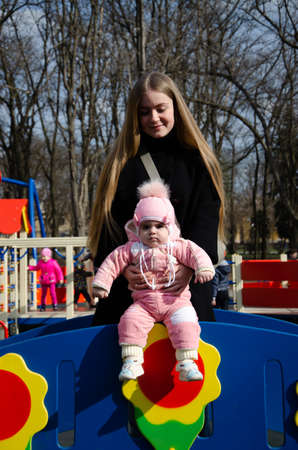 Mom plays on a bright playground with a small child in the street, nomads, a house during the dayの写真素材