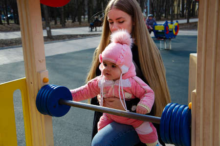 Mom plays on a bright playground with a small child in the street, nomads, a house during the dayの写真素材