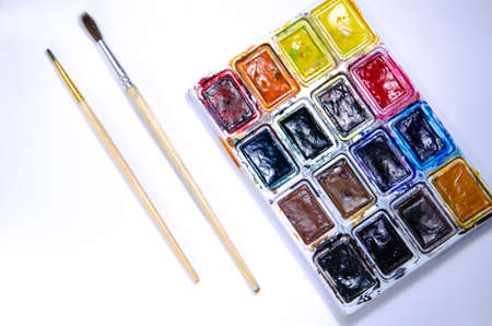 Palette with watercolors and brushes for paints on a white background. Watercolor paints. Brushes. Top and front viewの写真素材