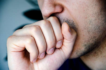 A man in close-up coughs in his hand, fist. Cough. Virus infection. Man with stubble.   COVID-19