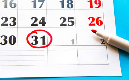 Calendar in close-up on a blue background. Red marker on the calendar. The 31th number in the...