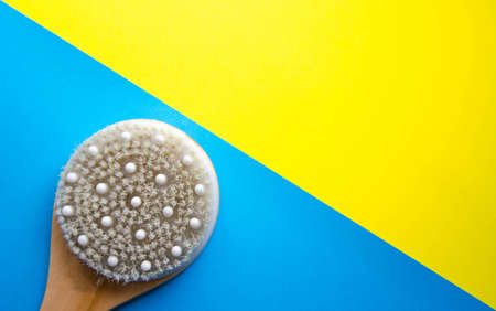 Dry massage. Brush made of natural cactus bristles, animals. Massage brush on a blue and yellow background from different angles. Place for text. Macro brush. Handle anti-cellulite brush.  Copy Spaceの写真素材