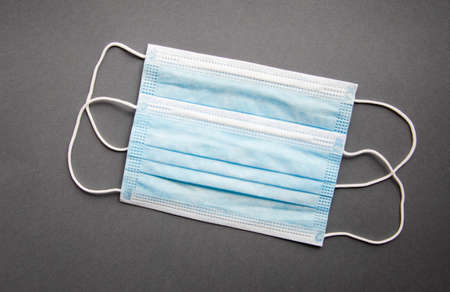 Two blue medical masks lie on a gray background. Mast in open and closed state. Place for text. Copy...