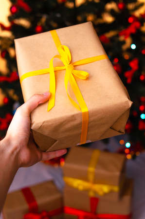 Boxes with gifts on a light, blue background and under the Christmas tree. Gift in the hand....