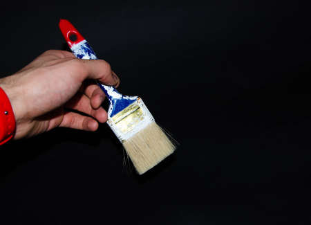 Used paint brush. Blue brush with a red tip in white paint. Macro photo. Repair brush in hand. Fibers Copy Spaceの写真素材