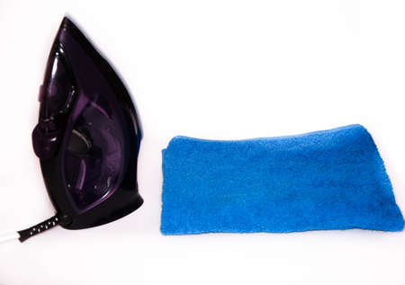 Modern iron on a white background with blue and white towels. View from the top, side. Macro. Iron...