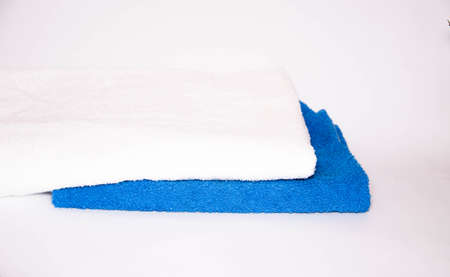 Ironed towels in blue and white on a white background. View from the top, side. Macro. Place for text. Towels on the table and in the foreground a green potted flowerの写真素材