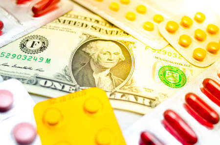 Dollars on a table around a plate with medicines and capsules. The medicine was bombarded with dollars. Corruption. Effect flare.の写真素材