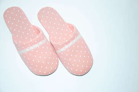 Women's pink warm slippers for the house with white polka dots on a white backgroundの写真素材