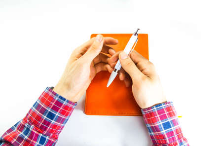 Men's hands, forearm hold a pen, notebook, smartphone. Hands write in notebook in a cell ideas,...