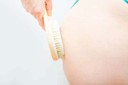 Dry massage. Massage at home, in the salon with a brush of natural bristles. Girl does massage legs, buttocks in close-upの写真素材