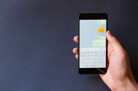 A male hand holds a smartphone, points a finger, types. Communication on a smartphone,...