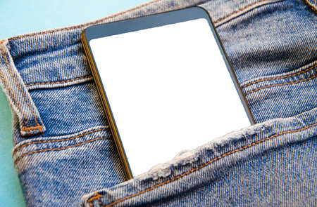 White screen smartphone in jeans pocket. Smartphone place for text. Smartphone in a pocket on a blue...