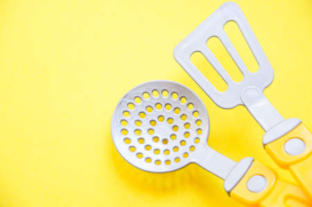 Toy tool for cooking. Ladle, slotted spoon, spatula for cooking on a yellow, blue, black background. Kitchen tools. Copy Spaceの写真素材