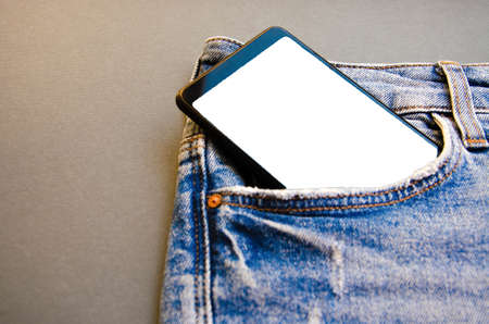 White screen smartphone in jeans pocket. Smartphone place for text. Smartphone in a pocket on a black background. Copy Spaceの写真素材