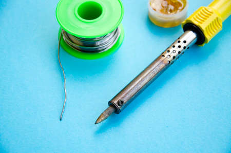 Soldering iron, tin, rosin on a yellow background. Macro. Repair of electrical equipment, radio engineering. Solder wires, contacts. Copy Spaceの写真素材