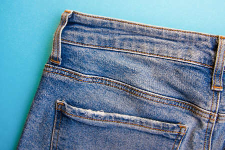 Jeans on a blue background. Jeans elements, pockets, seams in close-up. Ripped jeans. Copy Space