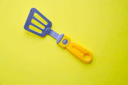 Toy tool for cooking. Ladle, slotted spoon, spatula for cooking on a yellow, blue, black background. Kitchen tools. Copy Spaceの写真素材