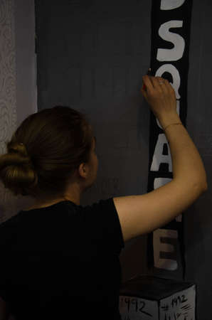 Young girl designer draws a city drawing with paints on a gray wallの写真素材