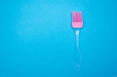 Silicone brush for lubrication on a blue background. Pink brush with transparent pen. Top view, from the first person. Macroの写真素材