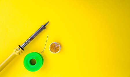 yellow Soldering iron, tin, rosin on a yellow background. Macro. Repair of electrical equipment, radio engineering. Solder wires, contacts. Copy Spaceの写真素材