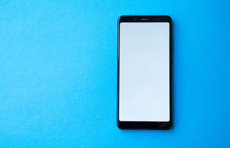 Smartphone top view on a blue and yellow background. Communication by smartphone. Talking on the phone. Correspondence, messengers. Copy Spaceの写真素材