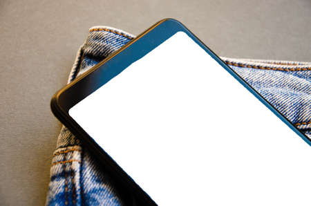 White screen smartphone in jeans pocket. Smartphone place for text. Smartphone in a pocket on a black background. Copy Spaceの写真素材