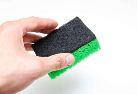 Sponge for washing dishes on a white background. Washcloth of green and yellow color. The male hand...