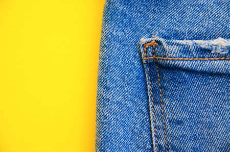 Jeans on a yellow background. Jeans elements, pockets, seams in close-up. Ripped jeans. Copy Spaceの写真素材