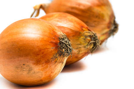 Three large onions lie in a row on a white background. Onions in macro go into the distance. Different-sized onionsの写真素材