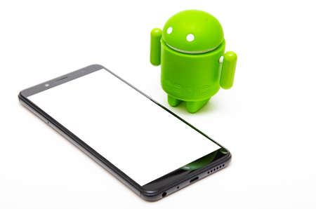 Android figurine and smartphone. Green android figurine made of ecological plastic on a white background in close-up lies a smartphone with a white screenのeditorial素材